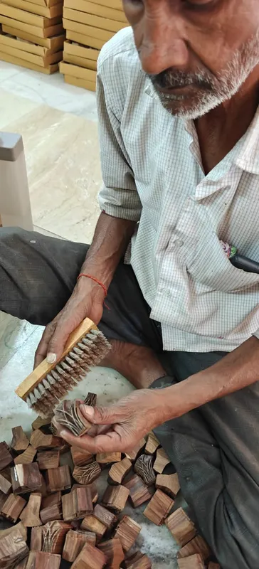 Brushing wood dust out of a freshly carved block